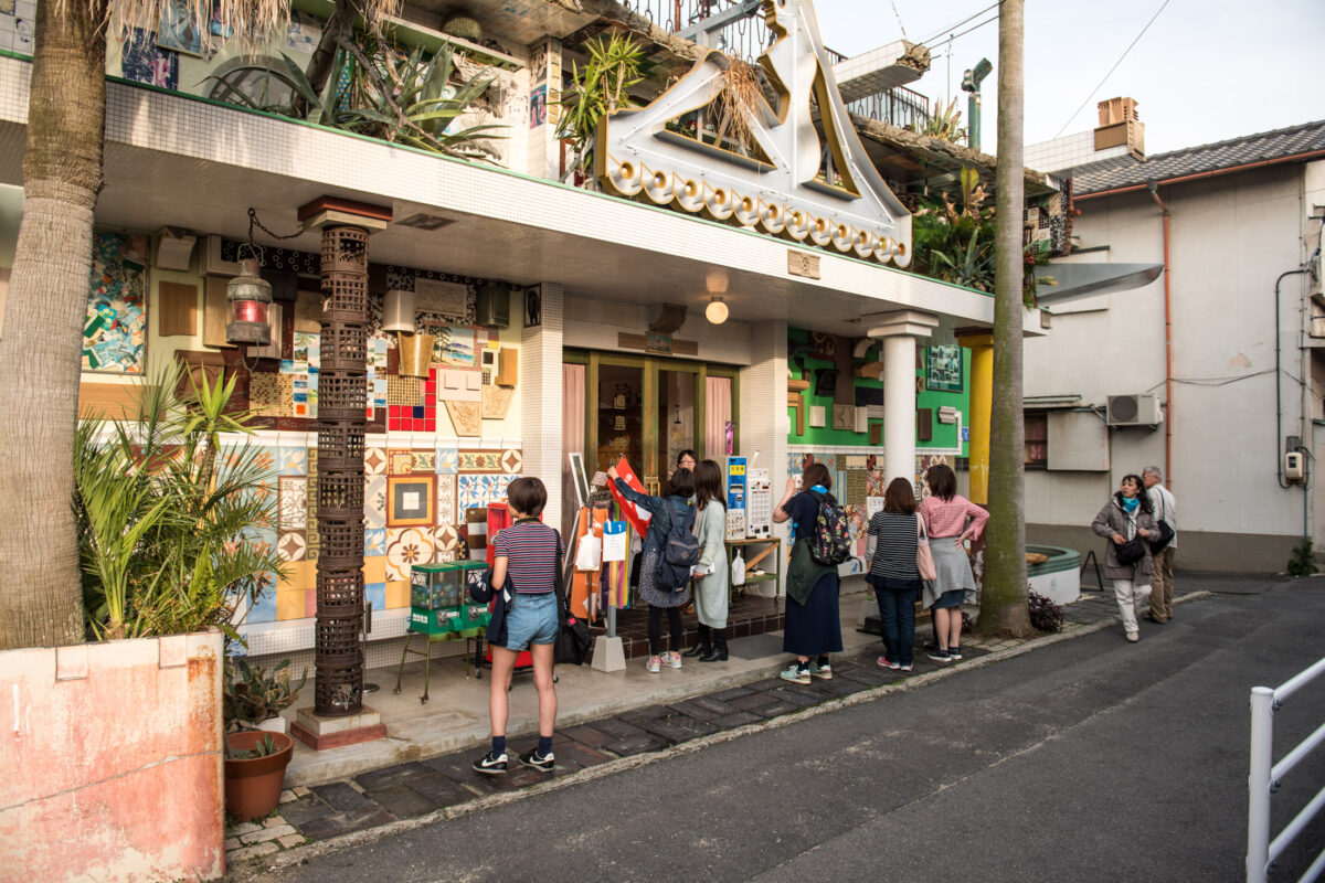 Colorful tile-covered street art building in Naoshima, Japan, with tourists outside