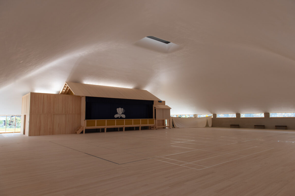 Minimalist wooden hall with curved ceiling and stage, Naoshima architecture interior
