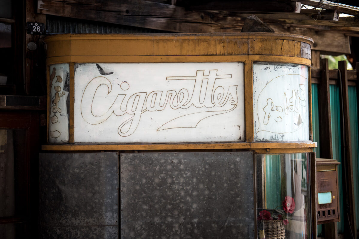 Weathered “Cigarettes” sign on Sekizenkan Ryokan exterior with aged wooden beams.
