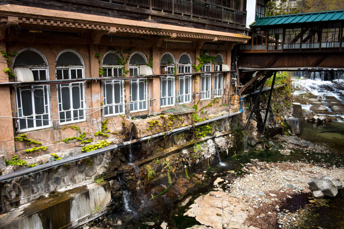 Sekizenkan Ryokan riverside onsen inn with arched windows and covered wooden bridge