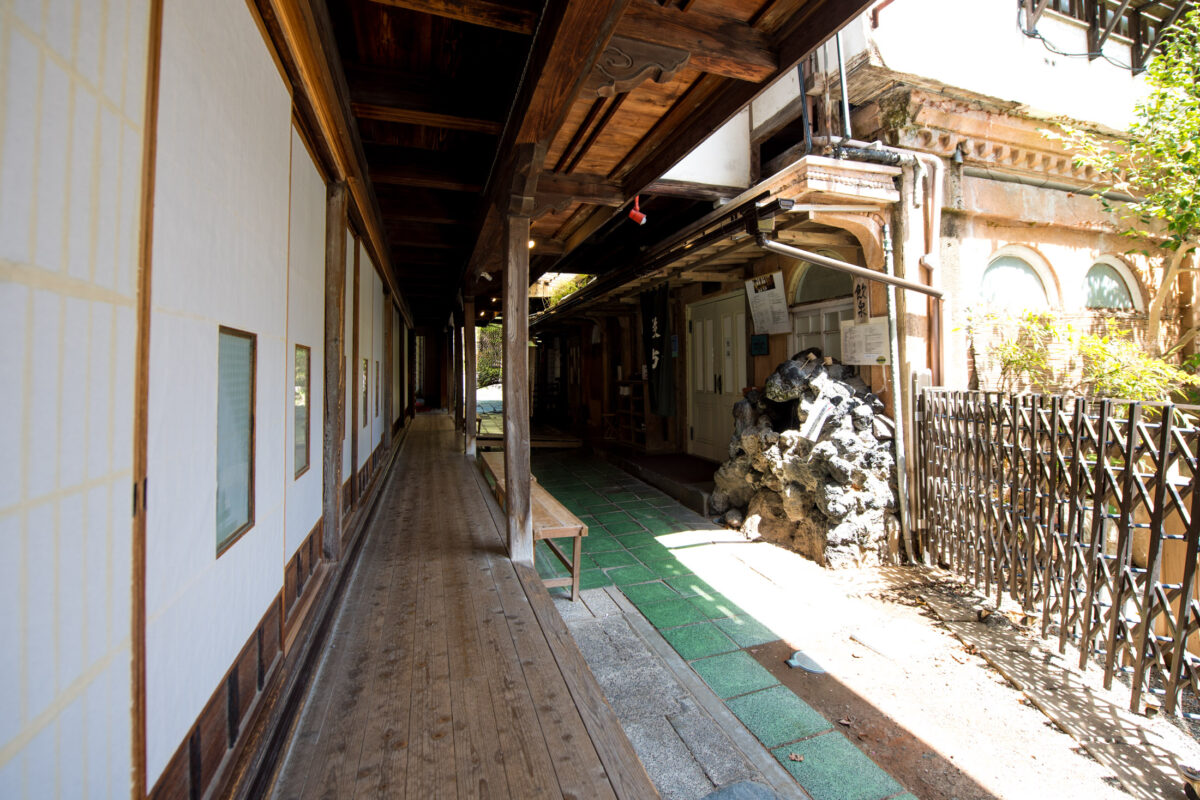 Historic wooden corridor at Sekizenkan Ryokan, Japan, with sunlit beams and plaster walls