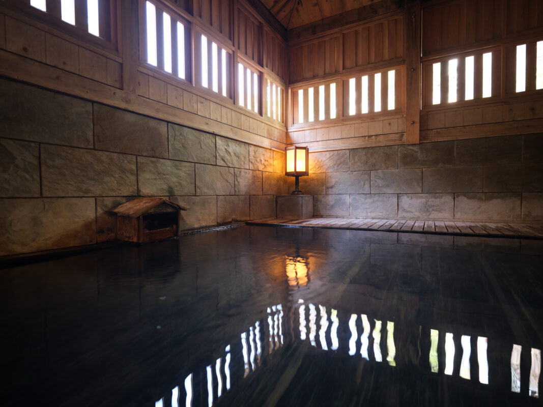 Serene indoor Japanese onsen bath with still hot spring pool and wooden walls