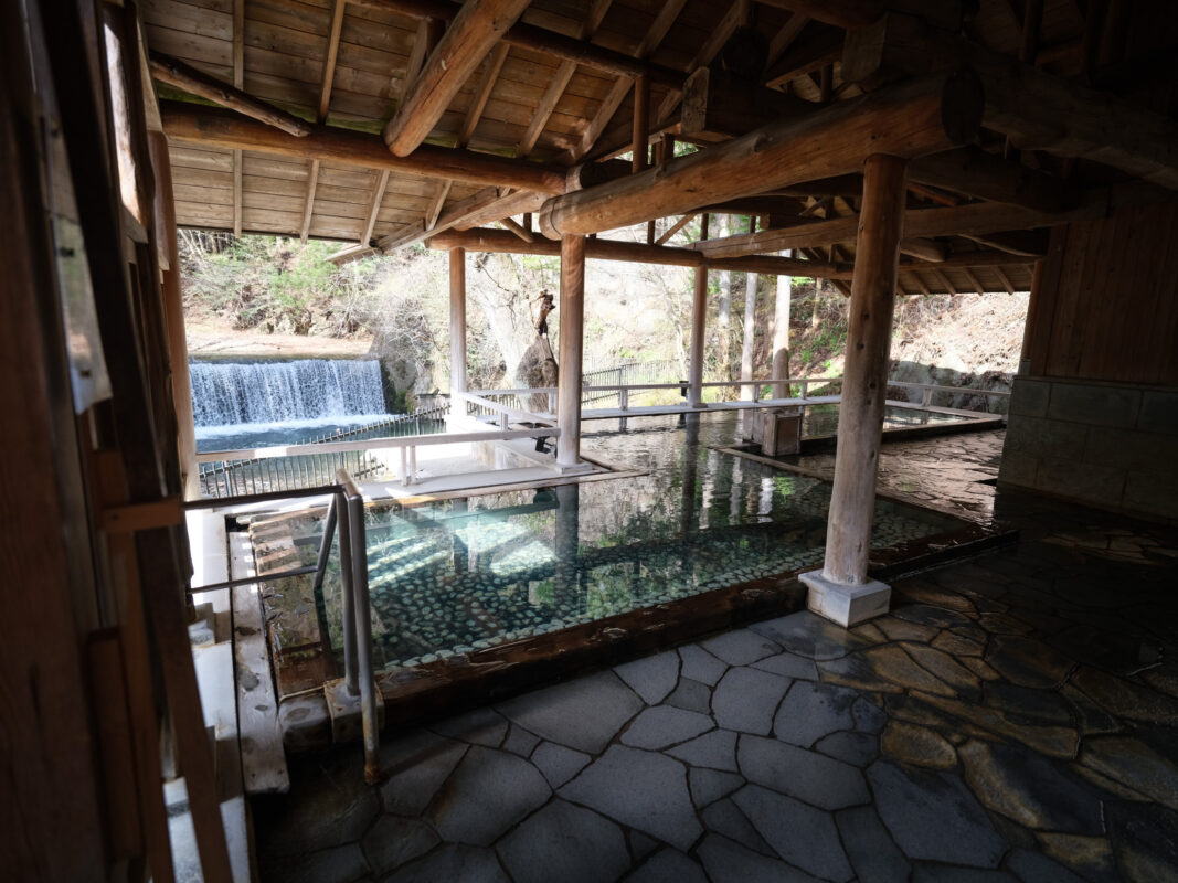 Shima Onsen rotenburo hot spring bath under wooden roof beside mountain stream