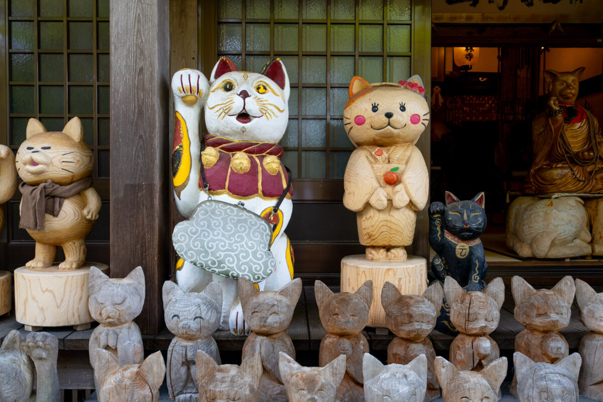 Maneki-neko and cat statues displayed in Unrin-ji temple alcove, Japan