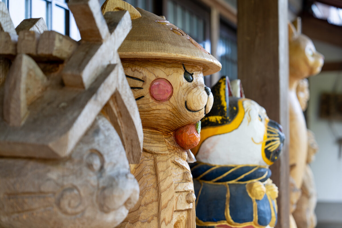 Wooden cat carvings on Unrin-ji Temple veranda in Japan, softly lit by natural light.
