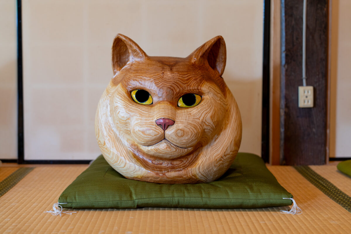 Wooden cat sculpture on green cushion atop tatami mats inside Unrin-ji Temple