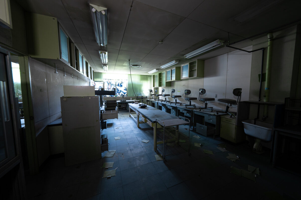 Abandoned animal research laboratory with long workbenches, sinks, and scattered papers.