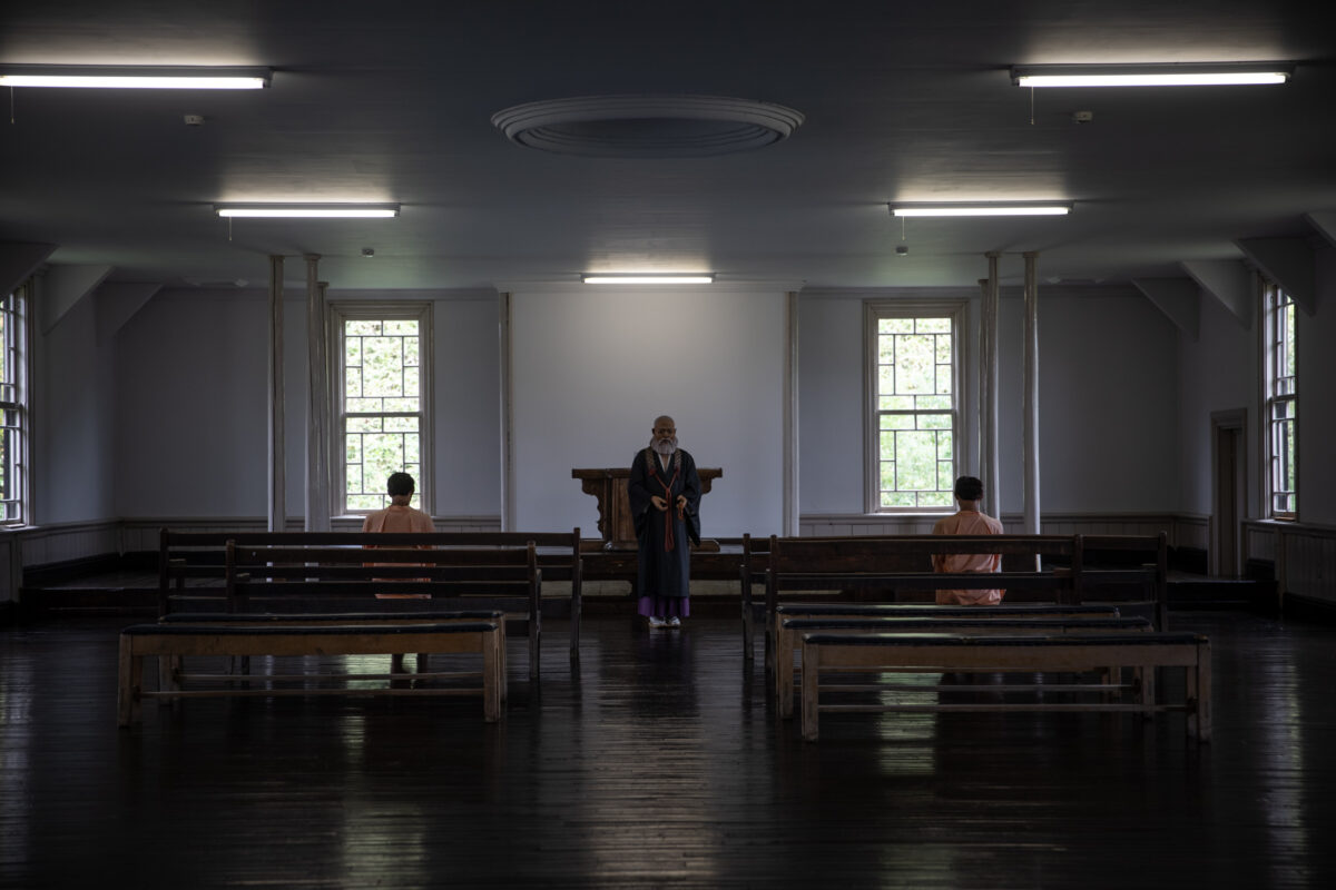 Symmetrical Abashiri Prison hall with wooden benches, glossy floor, and sparse visitors