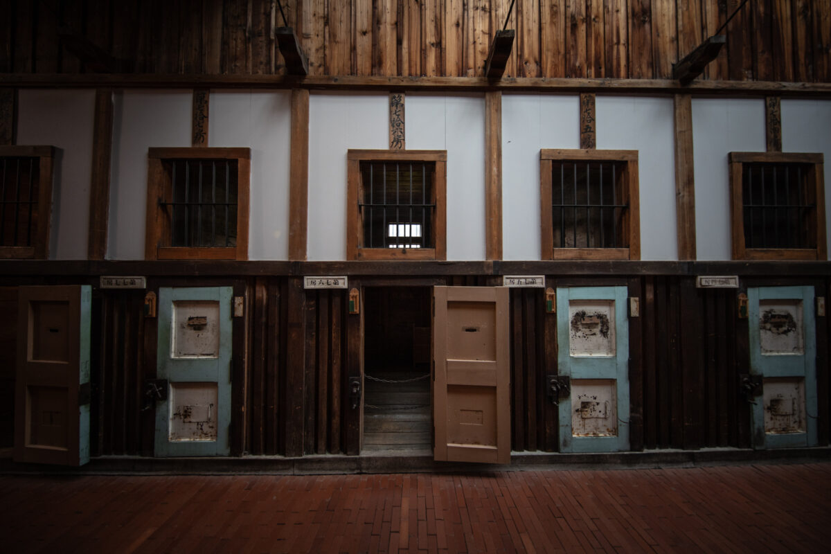 Historic Abashiri Prison cell block corridor with wooden doors, barred windows, and empty passageway.