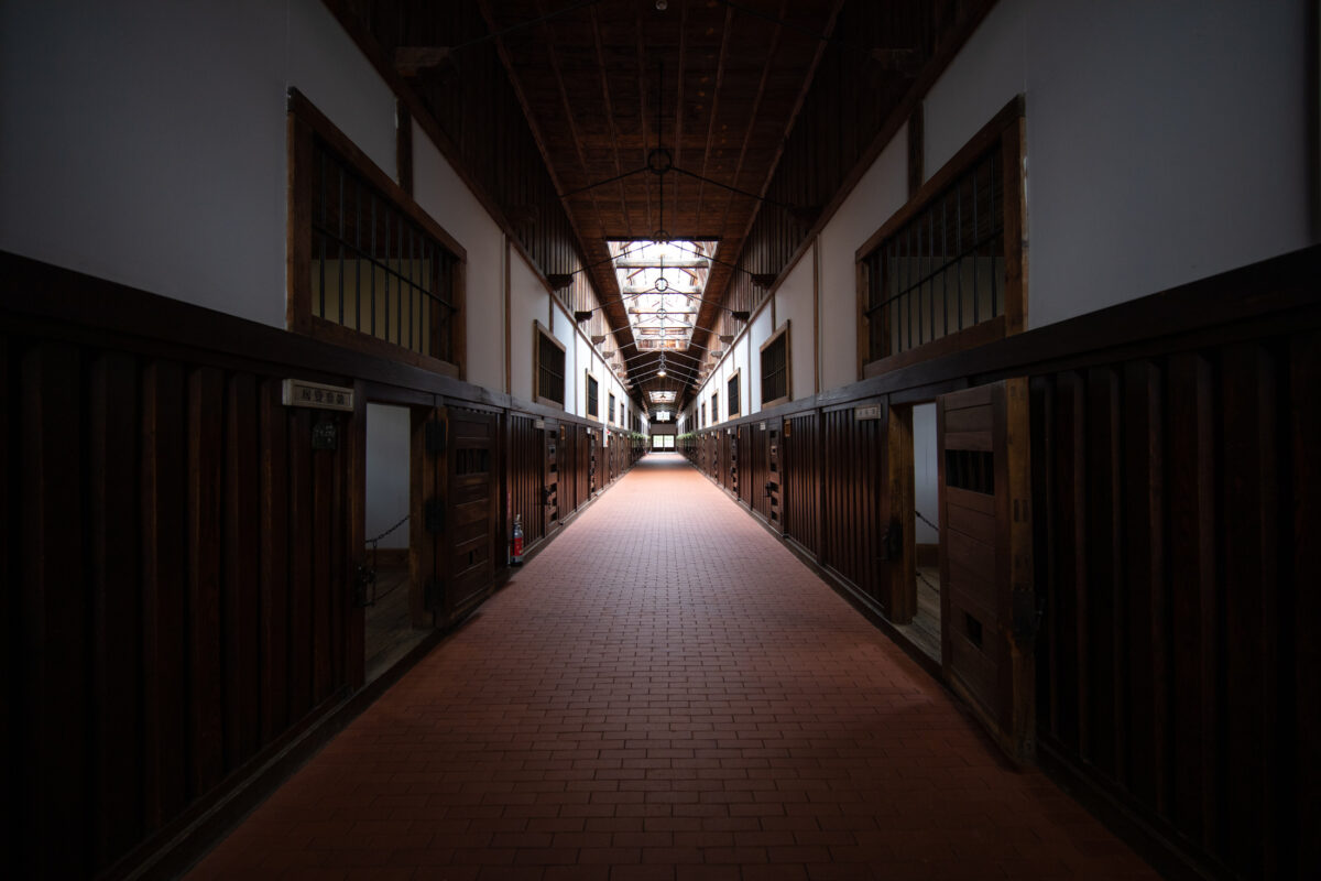 Abashiri Prison museum cellblock corridor with barred wooden doors and skylight perspective