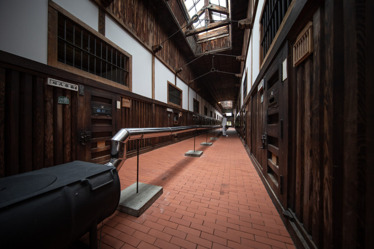 Abashiri Prison Japan wooden cellblock corridor with barred doors, brick floor, skylights