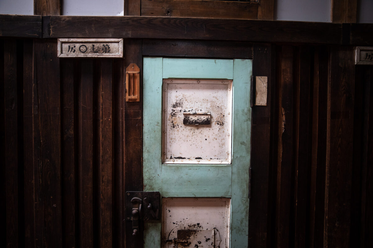 Weathered cell door with rusted panels inside Abashiri Prison museum in Japan