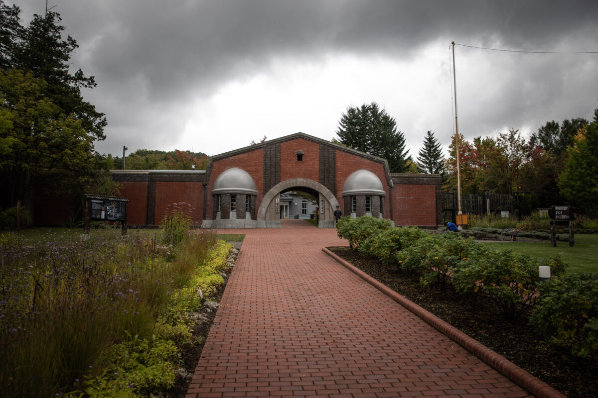 Abashiri Prison red brick entrance and arched gateway in Hokkaido, Japan under cloudy skies