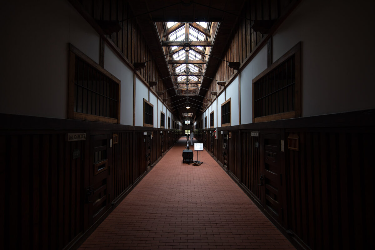 Abashiri Prison cellblock corridor with skylights, brick floor, wooden cell doors, and cleaning cart