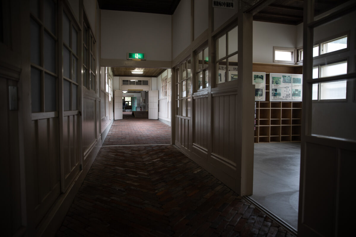 Long hallway inside Abashiri Prison Museum with wooden cell doors and brick floor