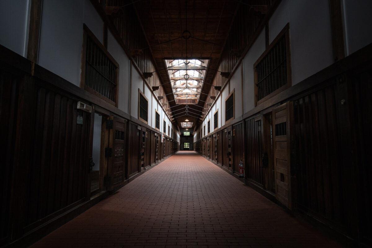 Symmetrical Abashiri Prison cellblock corridor with wooden cell doors and arched skylights
