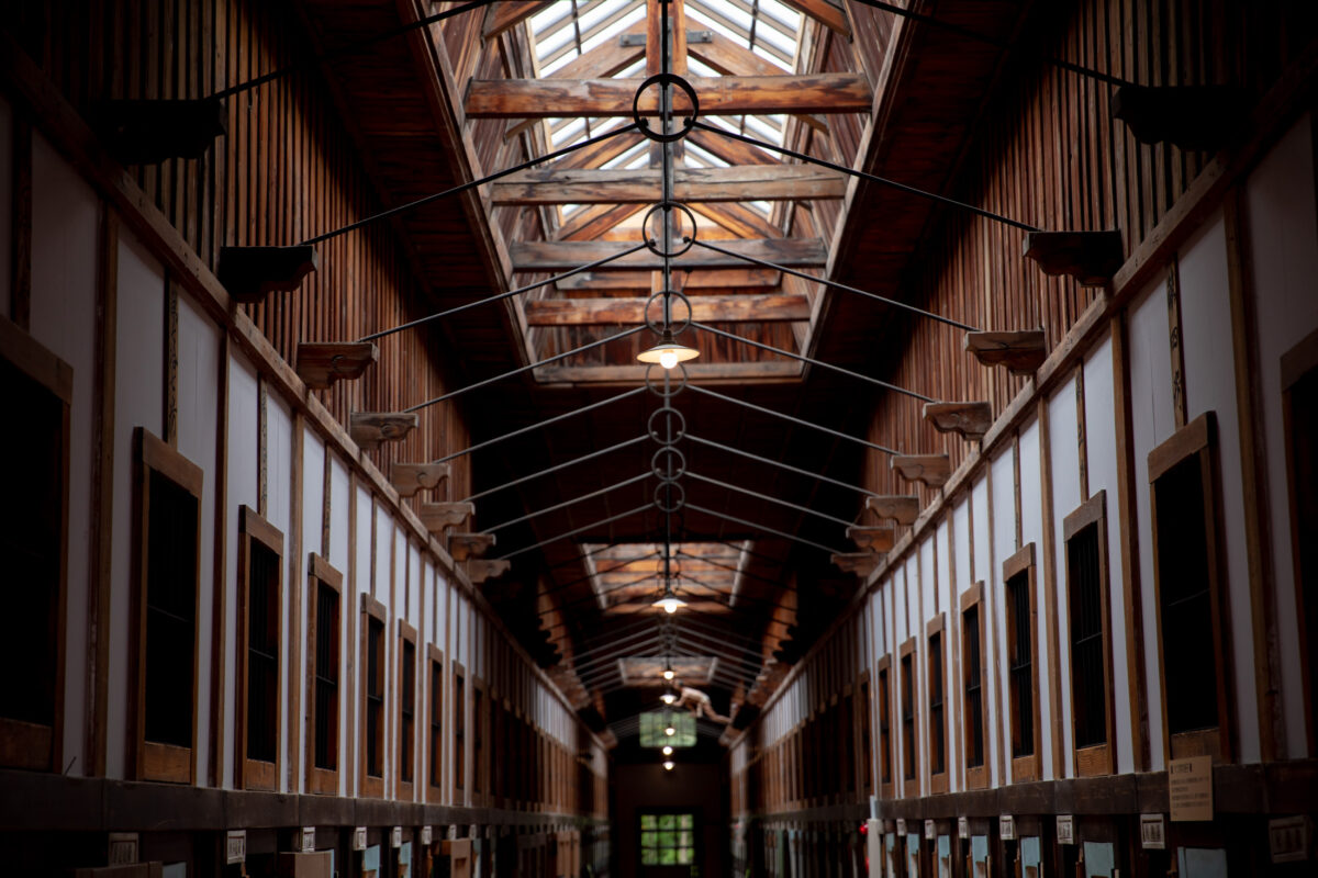 Empty wooden corridor inside Abashiri Prison with cell doors, exposed beams, and skylights.