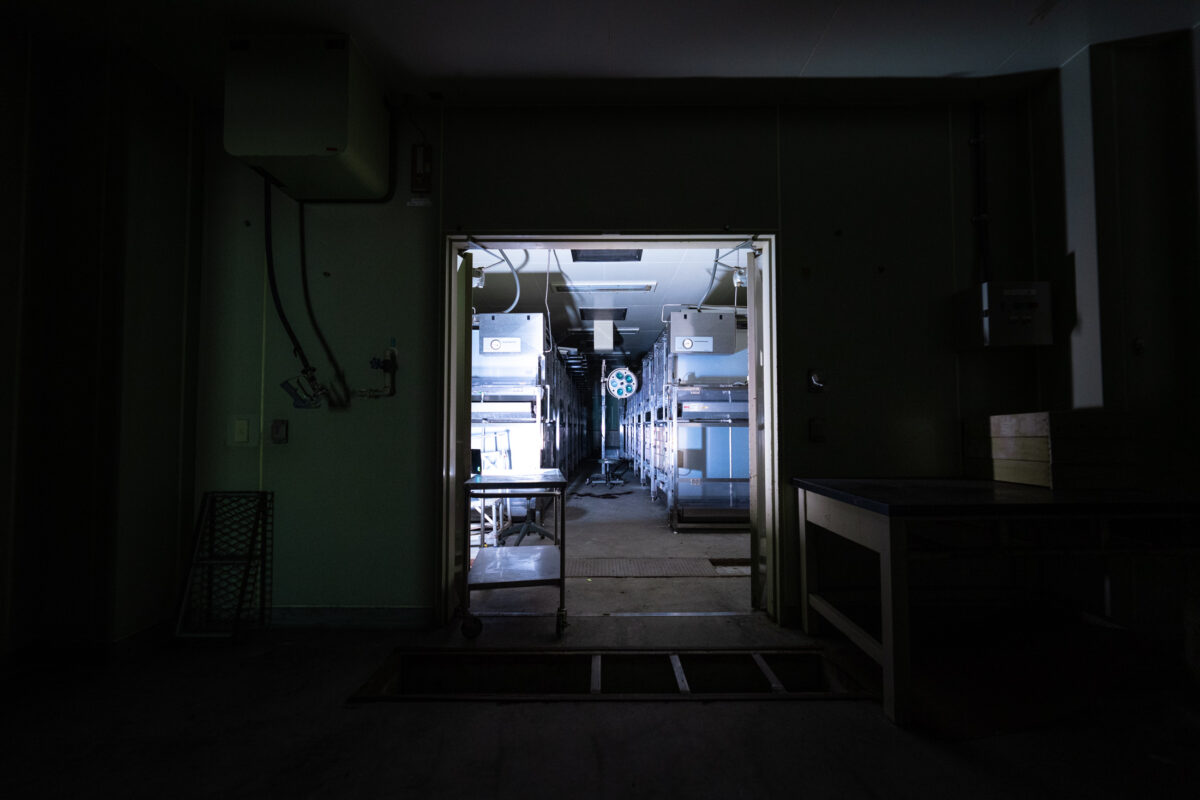 Abandoned animal research lab corridor with empty cages under fluorescent lights