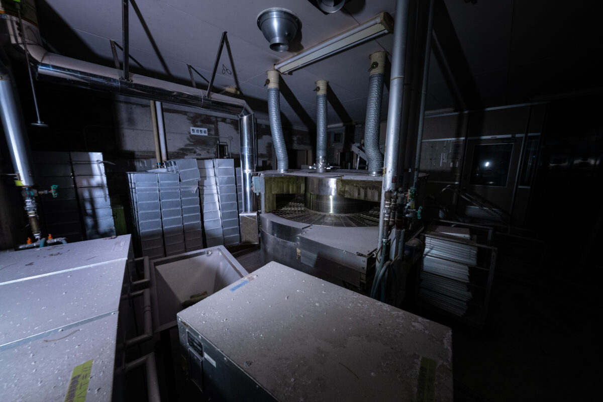 Dimly lit animal research lab interior with metal equipment, ducts, and storage units.