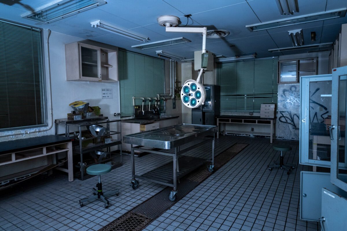 Abandoned animal research lab surgical room with operating table and overhead medical light.