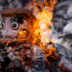 Daruma doll burning ritual at Shorinzan Temple, Japan, surrounded by flames and ash.