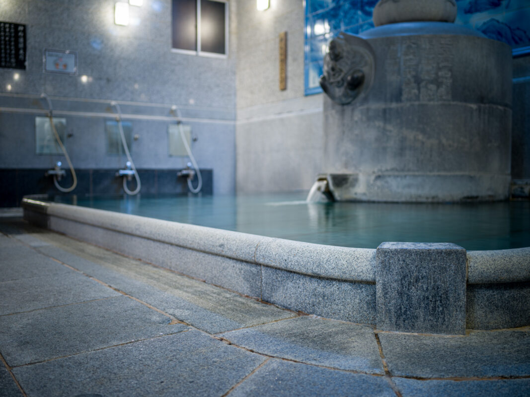 Dogo Onsen stone bath interior with clear hot spring pool and washing stations