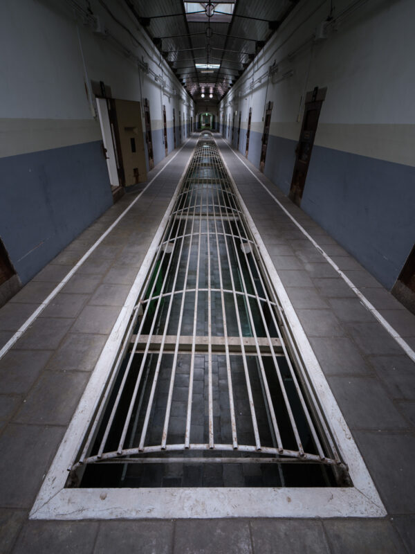 Historic Nara Prison corridor with cell doors and barred trench floor grates