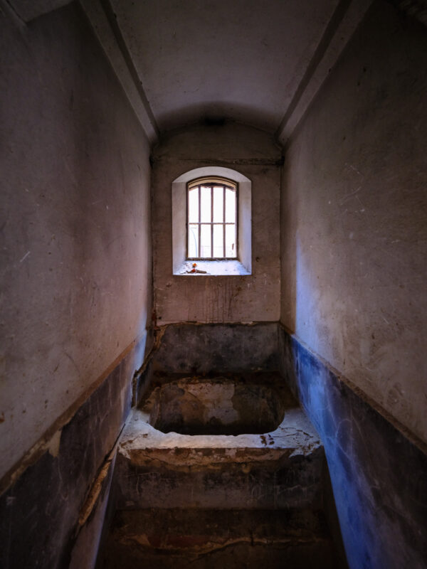 Barred window in Nara Prison stone cell, narrow corridor with steps and worn walls