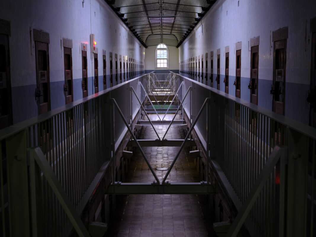 Symmetrical cell block corridor in Nara Prison with barred doors, walkways, and arched window.