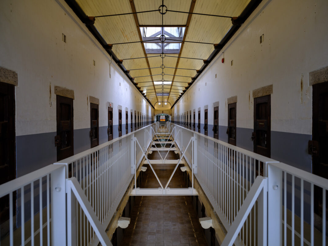 Symmetrical cellblock corridor in Nara Prison with skylight, metal walkway, and closed doors.