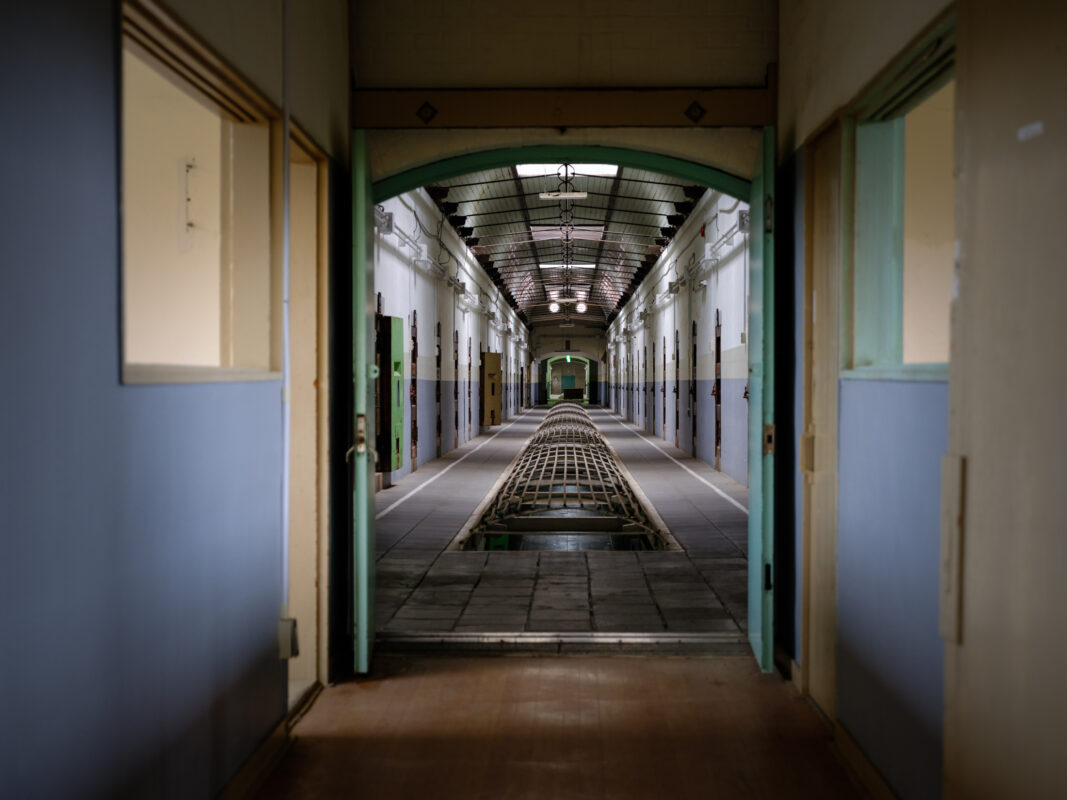 Empty corridor inside Nara Prison, symmetrical cell doors and barred floor channel.