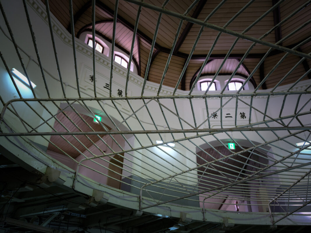 Upward view of Nara Prison rotunda with iron bar grid, Japanese signage, arched windows