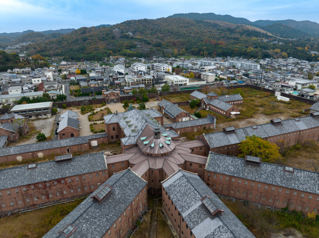 Aerial view of historic Nara Prison, Japan, showing radial red-brick cellblocks and central hub.