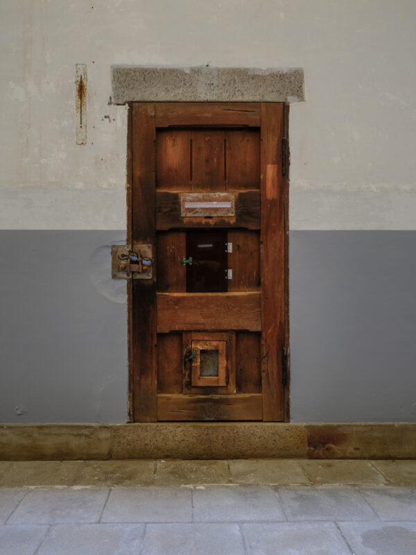 Weathered wooden cell door with metal locks at historic Nara Prison, Japan