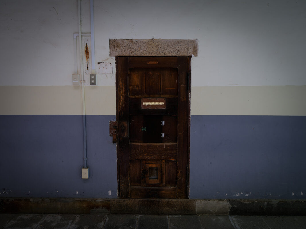 Weathered wooden prison door with viewing slot inside historic Nara Prison, Japan.