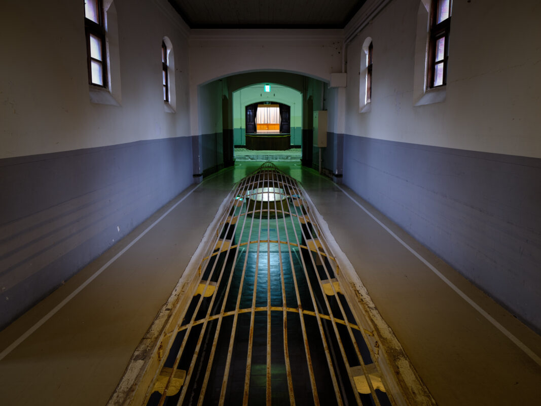 Historic Nara Prison corridor with metal floor grate and arched doorway light