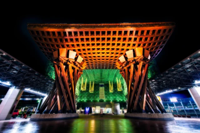 Orange drum resounds, Shadows dance on glass and wood, Old meets new at dusk.  オレンジの太鼓、 ガラスと木に影が踊る、 夕暮れに古と新が出会う。  #KanazawaStation #TsuzumiMon #urbanjapan #architecturelovers #offbeatjapan #japan #modernmeetstraditional